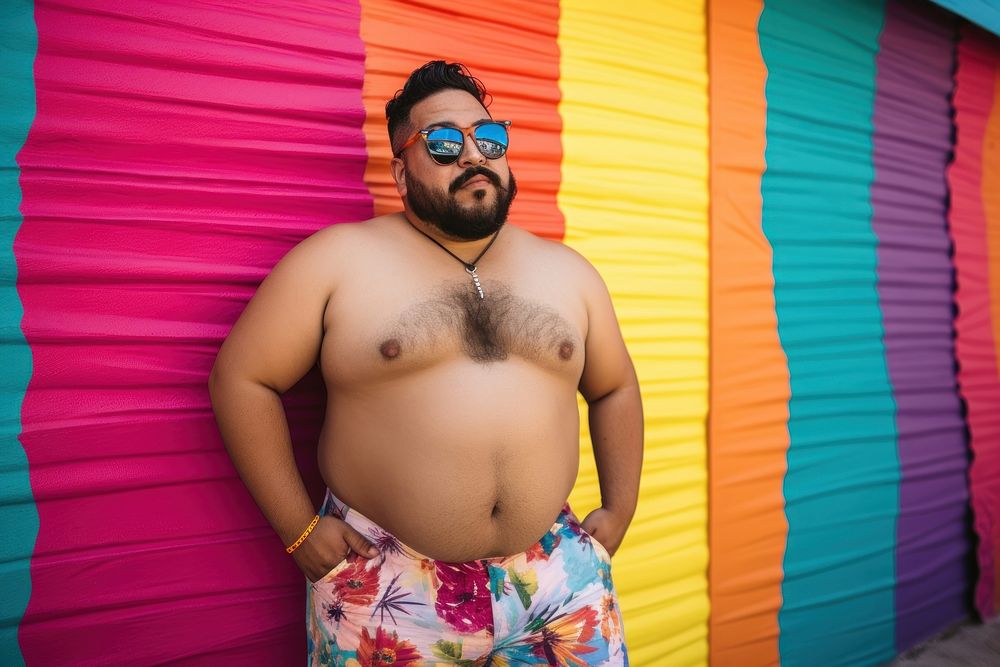 Chubby Latino man in a swimming pants standing in front of a colorful wall sunglasses portrait fashion. AI generated Image…
