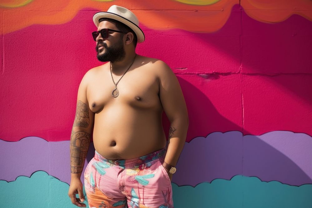 Plus size Latino man in a swimming pants standing in front of a colorful wall portrait fashion tattoo. AI generated Image by…