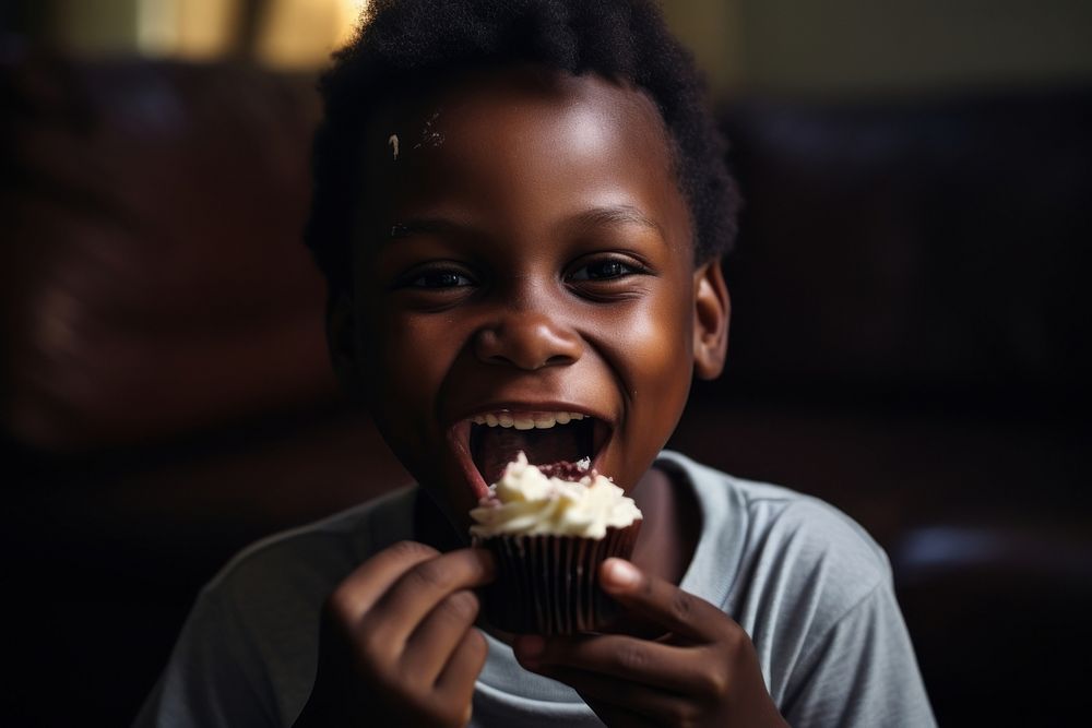 Black boy eating cupcake smiling biting child. AI generated Image by rawpixel.