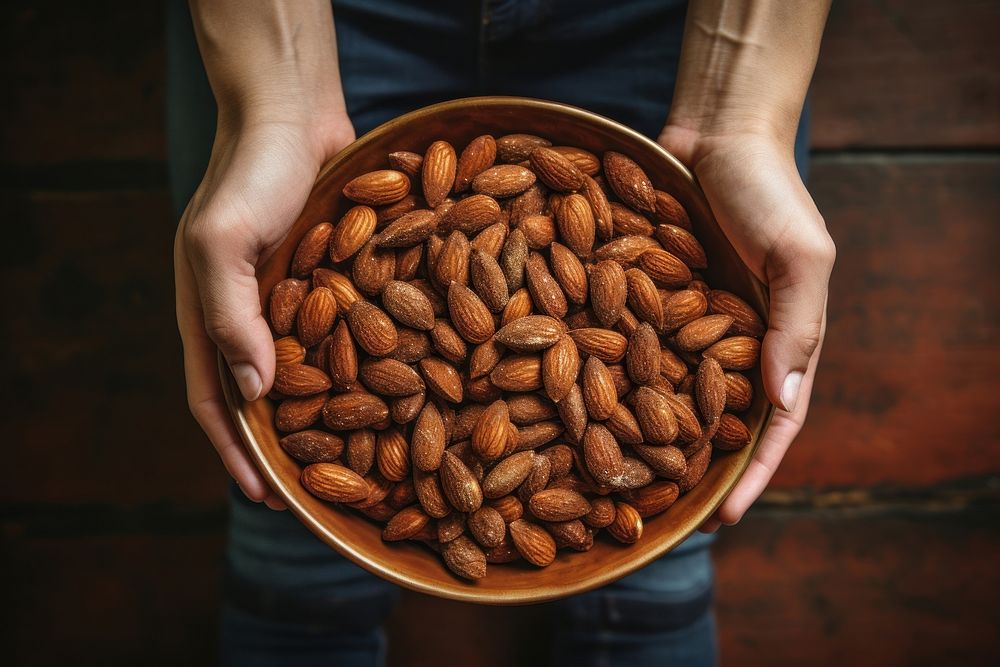 A plate of roast almonds holding food hand. AI generated Image by rawpixel.