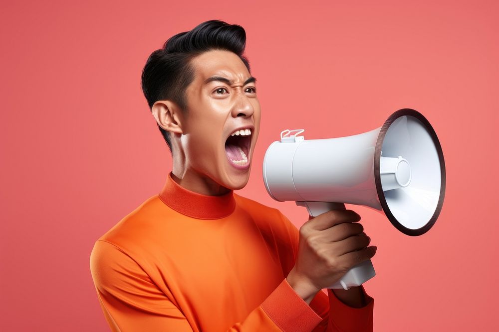 Thai man using megaphone shouting adult technology. AI generated Image by rawpixel.