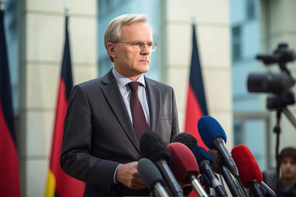 Middle age male German official talking in the press conference microphone speech adult. AI generated Image by rawpixel.
