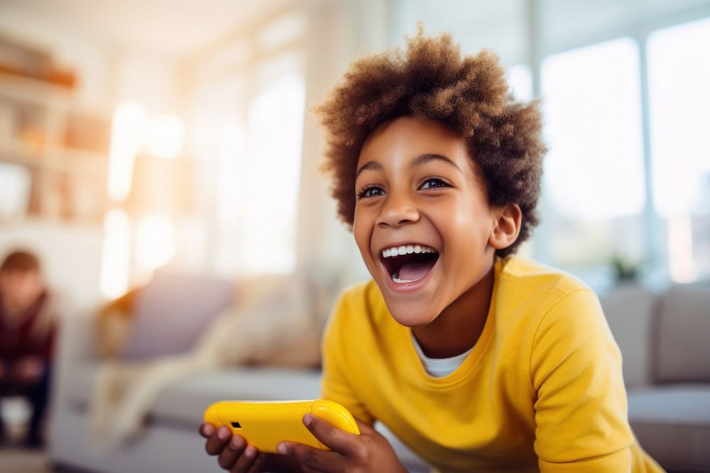Boy in yellow sweater playing with a controller laughing technology relaxation. AI generated Image by rawpixel.