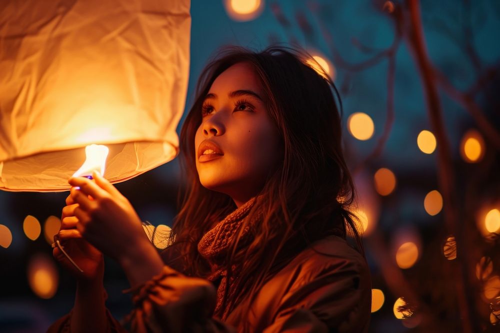 A woman holding a sky lantern outdoors night illuminated. AI generated Image by rawpixel.