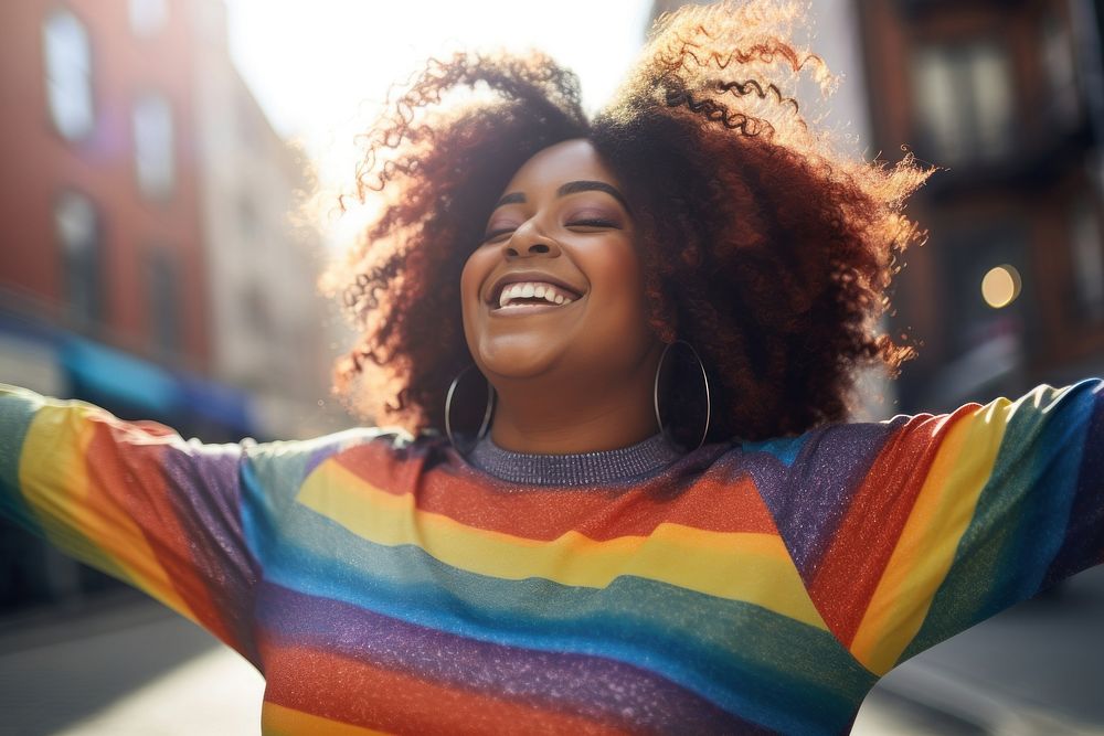 A chubby black woman in a rainbow knit shirt laughing outdoors smiling. AI generated Image by rawpixel.