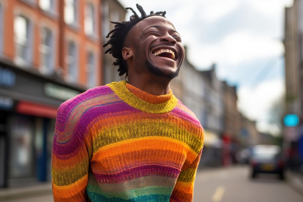 A black man in a rainbow knit shirt laughing outdoors smiling. AI generated Image by rawpixel.