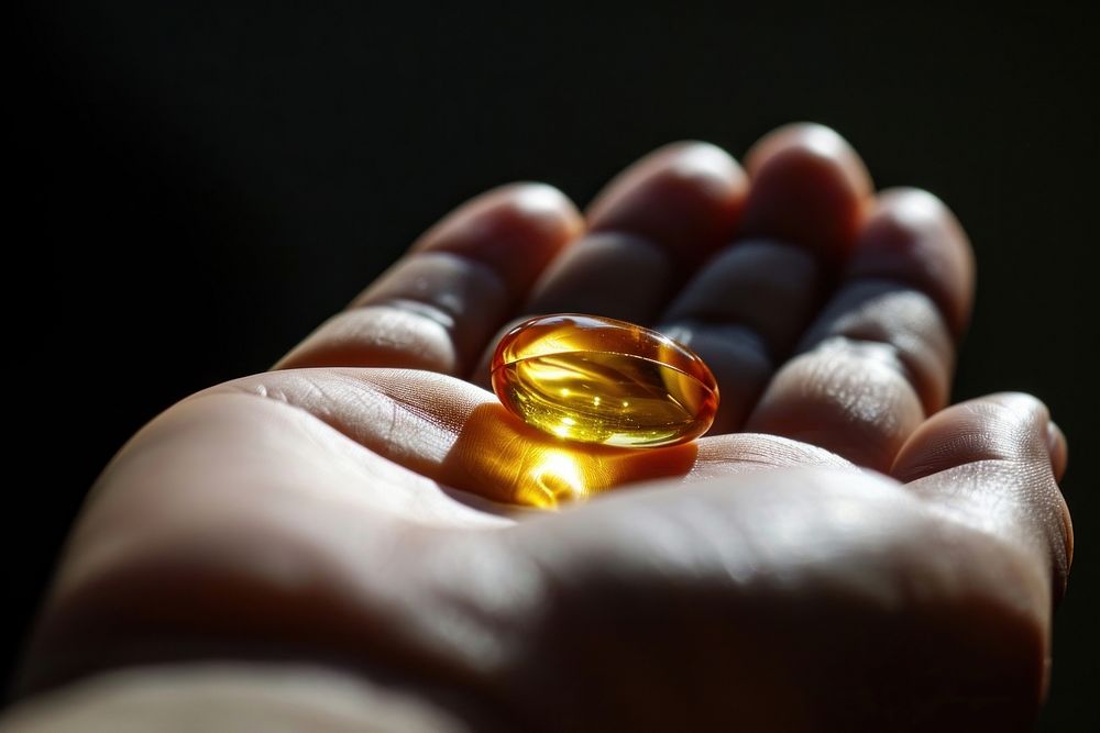 Fish oil pill jewelry holding hand. AI generated Image by rawpixel.