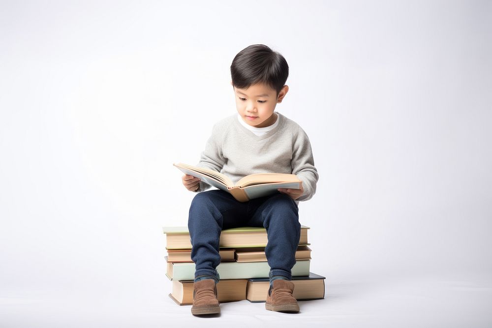 Asian boy reading book sitting publication child. AI generated Image by rawpixel.