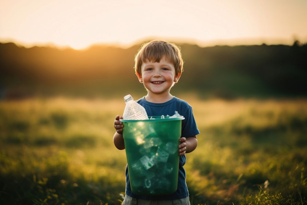 Kid holding a recycle bin grass field portrait. AI generated Image by rawpixel.
