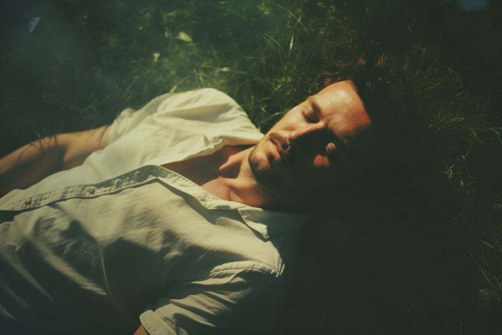 A man laying comfortably in the grass photography sleeping portrait. AI generated Image by rawpixel.