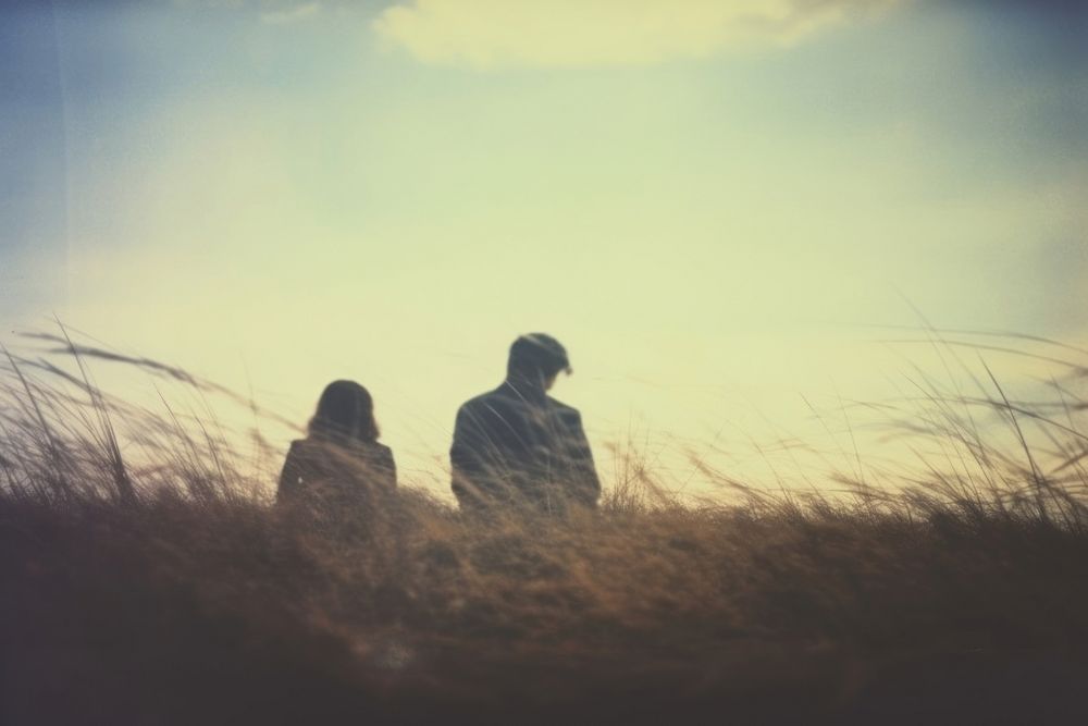 A far away couple sitting on top a grass covered field photography landscape outdoors. AI generated Image by rawpixel.