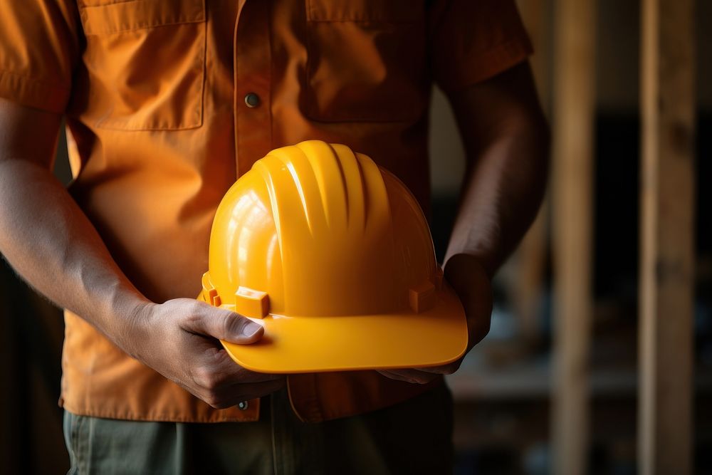 A person holding a yellow hard hat beside the waist hardhat helmet adult. AI generated Image by rawpixel.