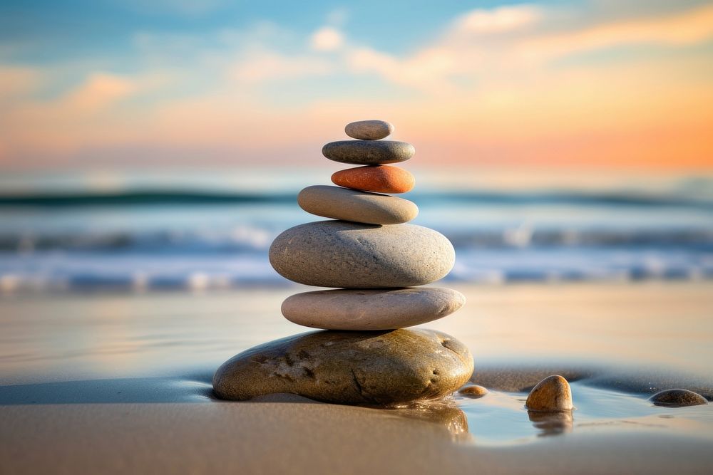 Stones stacked in the sand pebble sea spirituality. AI generated Image by rawpixel.