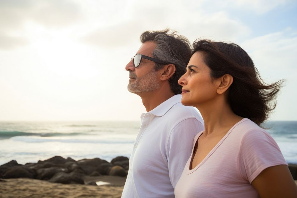 Latina brazillian middle age Loving couple standing at beach shore while looking away portrait outdoors summer. AI generated…