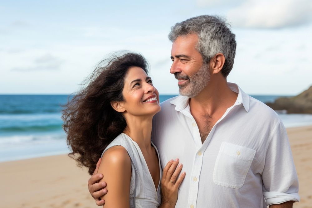 Latina brazillian middle age Loving couple standing at beach shore while looking away summer adult togetherness. AI…