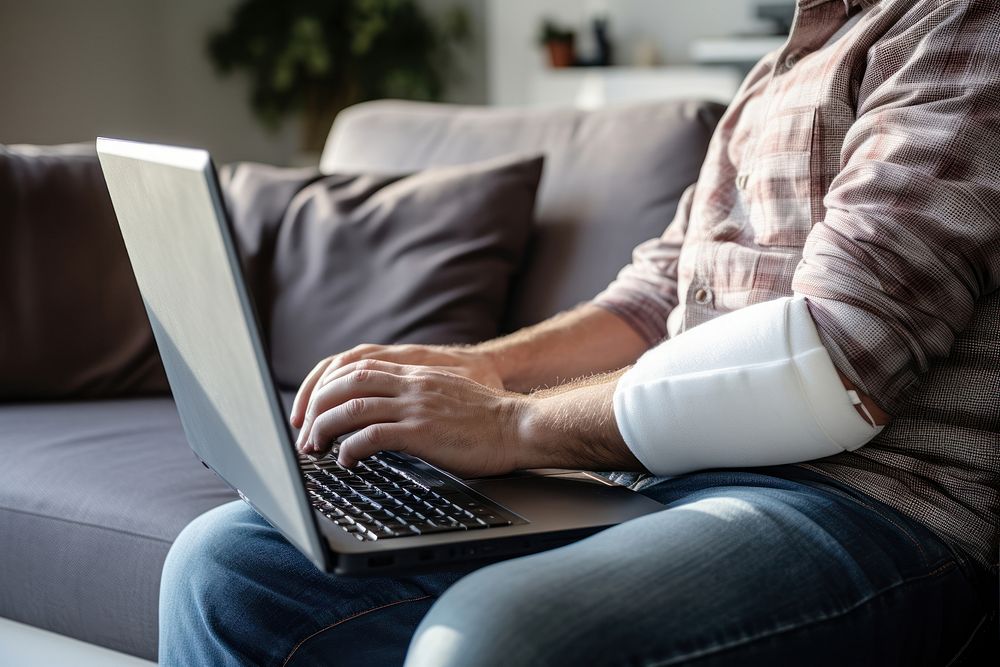 Man with a splint on arm laptop furniture computer. AI generated Image by rawpixel.