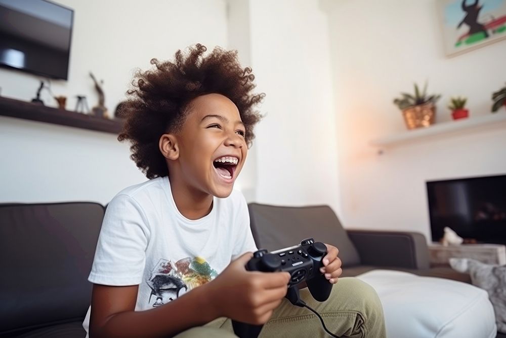 Black kid holding joystick laughing happy electronics. AI generated Image by rawpixel.