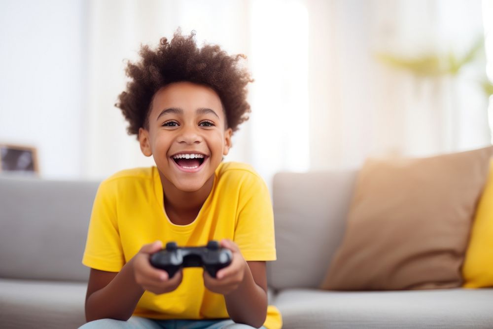 Black kid in yellow t shirt holding joystick laughing smile happy. AI generated Image by rawpixel.