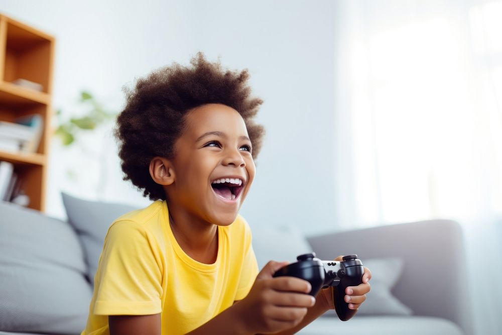 Black kid in yellow t shirt holding joystick laughing happy photo. AI generated Image by rawpixel.