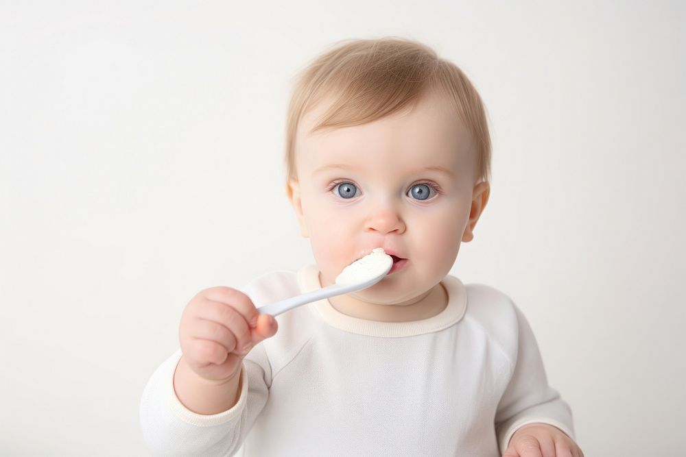 Baby eats porridge spoon toothbrush innocence babyhood. AI generated Image by rawpixel.