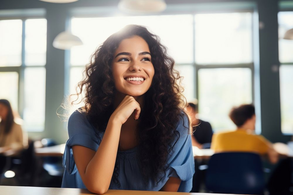 Latina student woman sitting at table laughing in classroom person smile adult. AI generated Image by rawpixel.