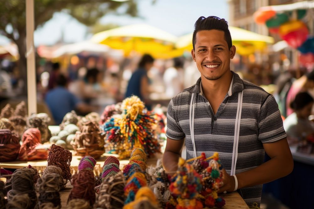 A young Latino entrepreneur showcasing handmade crafts at a vibrant street market creativity smile adult. AI generated Image…