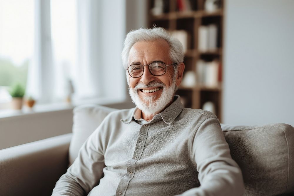 Elderly man smiles as he sits on the couch glasses adult contemplation. AI generated Image by rawpixel.