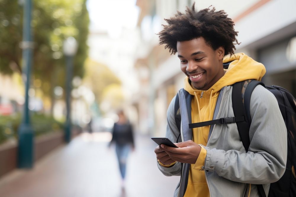 Smiling African student in backpack looking at cellphone on street adult architecture portability. AI generated Image by…