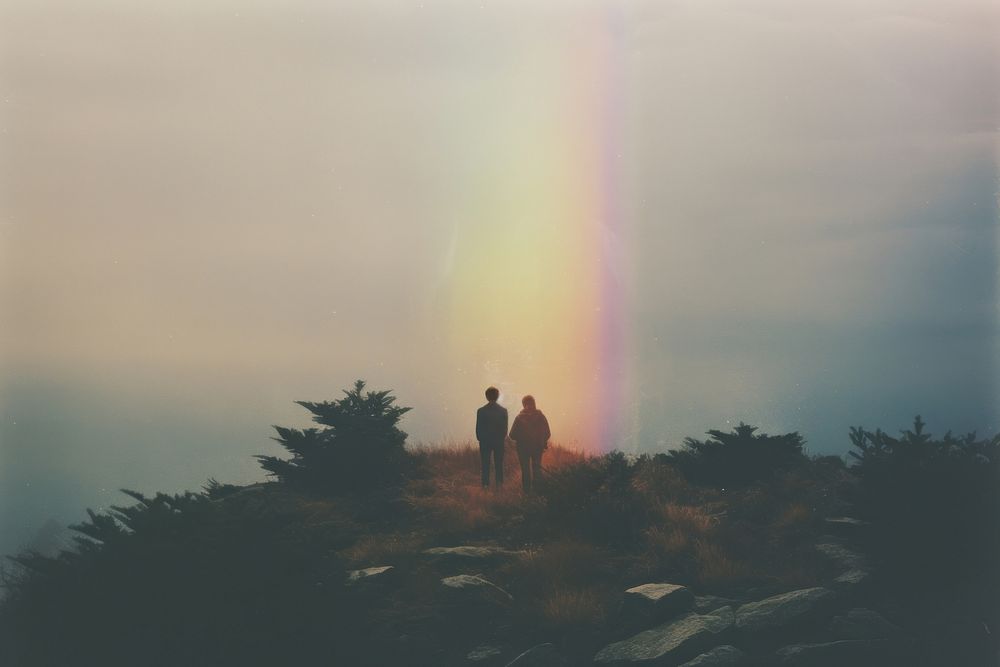 A couple with a backpack standing on top of a rock with bush rainbow silhouette landscape. AI generated Image by rawpixel.