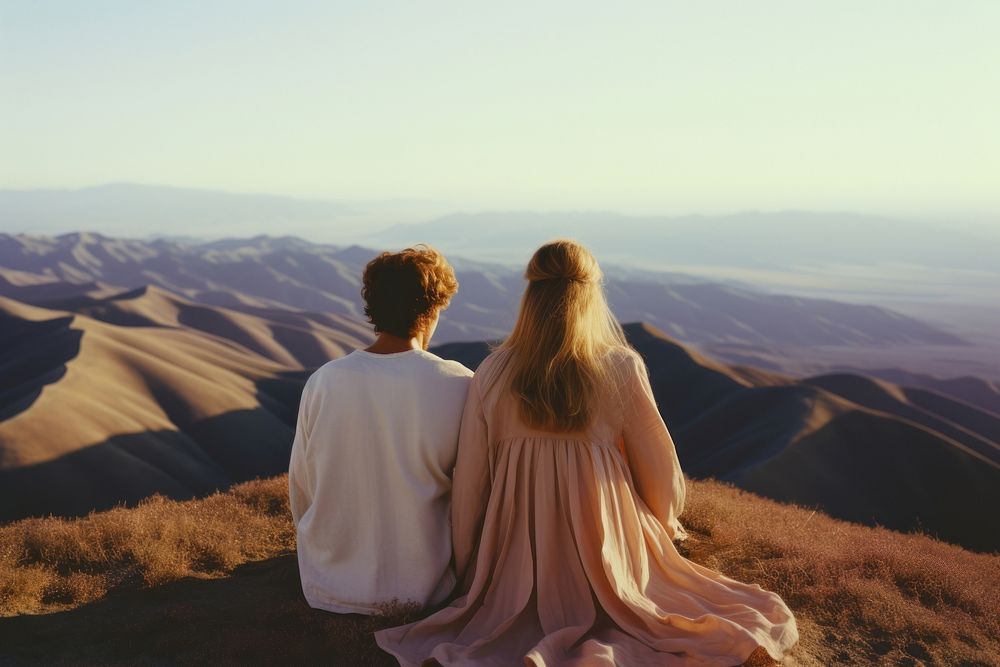 A hippie couple wearing wedding dress with hills background landscape photography outdoors. 