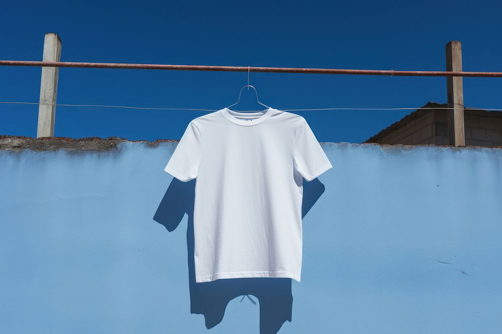 A t-shirt is hanging onto a barricaded fence sleeve white blue. AI generated Image by rawpixel.