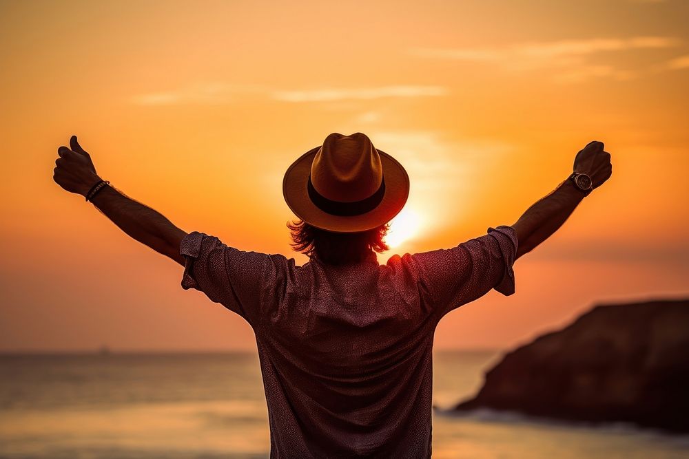 Happy man weating a hat with arms up enjoy freedom at the beach at sunset outdoors adult happy. AI generated Image by…