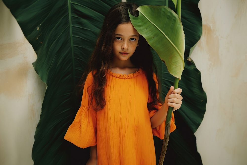 A girl wearing orange dress carry a banan leaf photography portrait plant. AI generated Image by rawpixel.