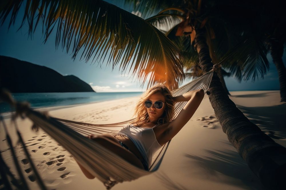 A blonde hair woman sleeping in a hammock under the coconut tree on the beach sea outdoors vacation. 