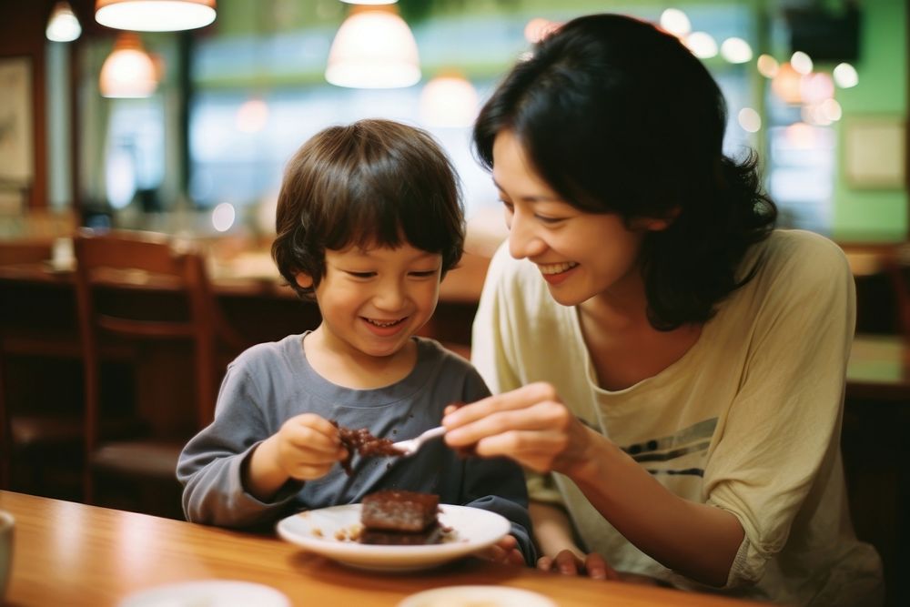 Mom feeding son chocolate cake at a yakuni sushi restaurant portrait eating child. AI generated Image by rawpixel.