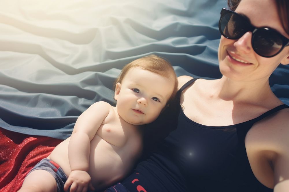 Mom on a beach mat with a baby in tow photography sunglasses portrait. AI generated Image by rawpixel.