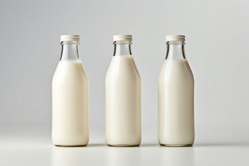 Three milk bottles of varying heights dairy drink white background. AI generated Image by rawpixel.