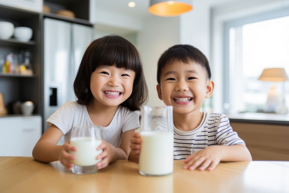 Young asian brother and sister drinking a glass of milk in kitchen togetherness refreshment friendship. AI generated Image…