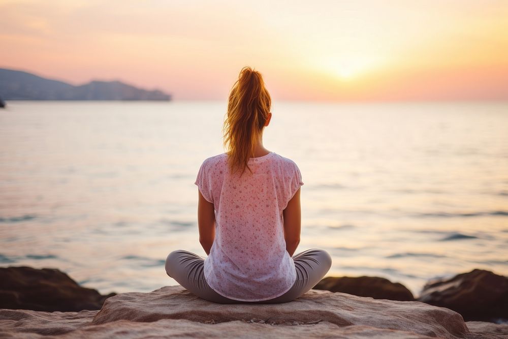 A Caucasian woman practicing yoga at seashore outdoors sitting nature. AI generated Image by rawpixel.