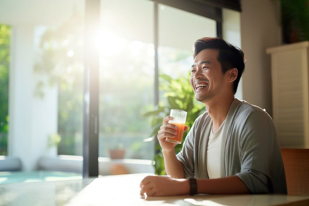 A Smiling asian man drinking detox juice at home smiling adult happy. AI generated Image by rawpixel.