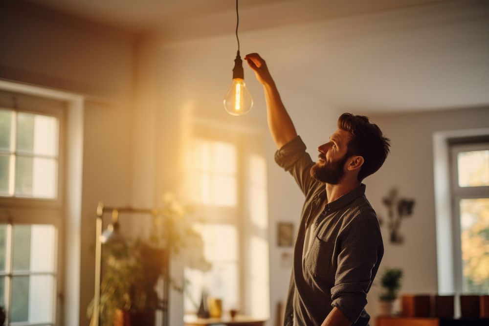 A man changing light bulb in hanging lamp at home lighting adult architecture. AI generated Image by rawpixel.