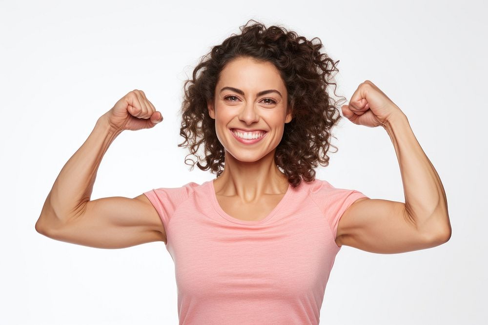 A Portrait of confident strong happy young woman looking at camera with smile and flexing her arm portrait adult white…