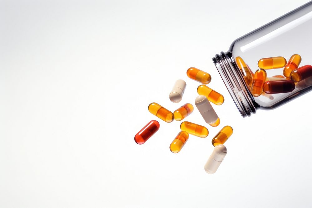 Capsules spilling out of bottle white background medication container. AI generated Image by rawpixel.