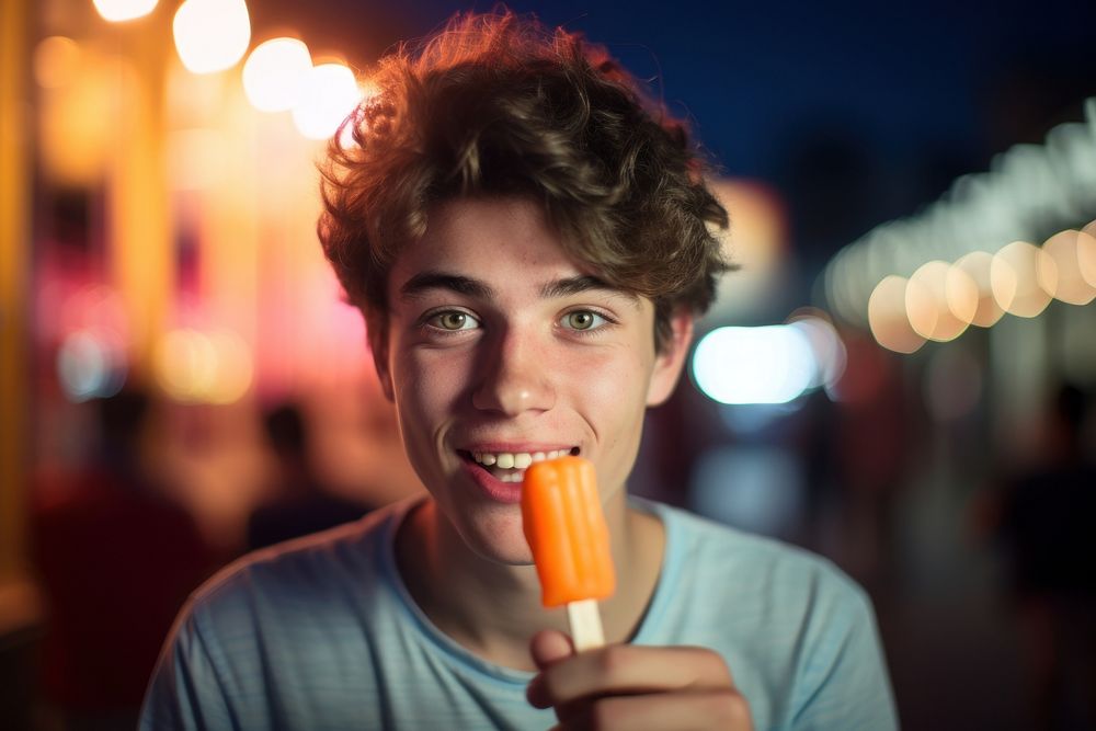 Young man eating orange ice lolly adult food face. 