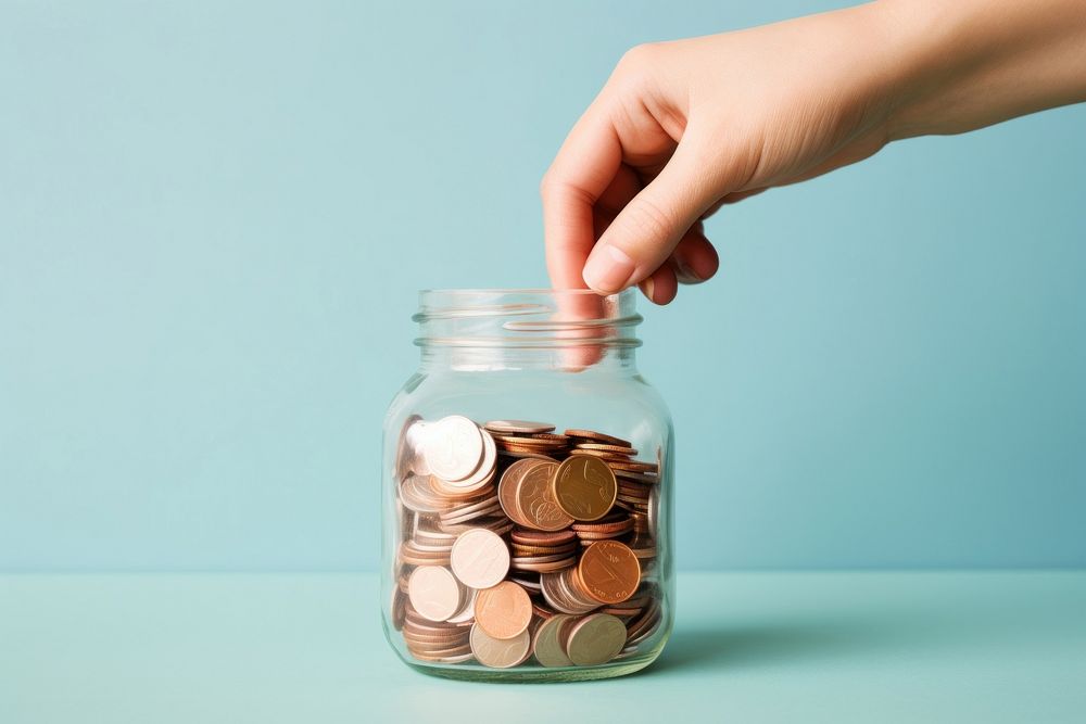 Hand holding coins in jar investment medication container. AI generated Image by rawpixel.