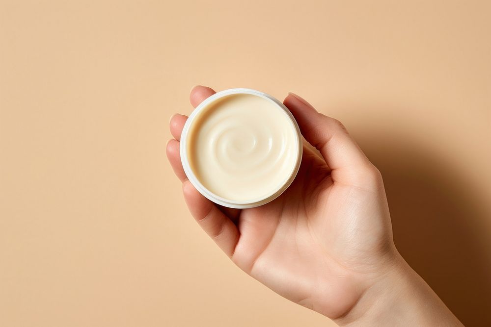 Hand holding moisturizer container finger cream cup. AI generated Image by rawpixel.