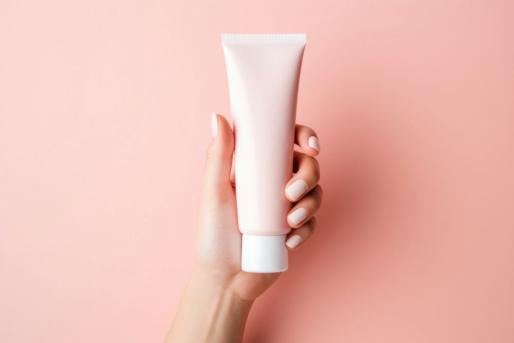Hand holding skincare tube cosmetics pink pink background. AI generated Image by rawpixel.
