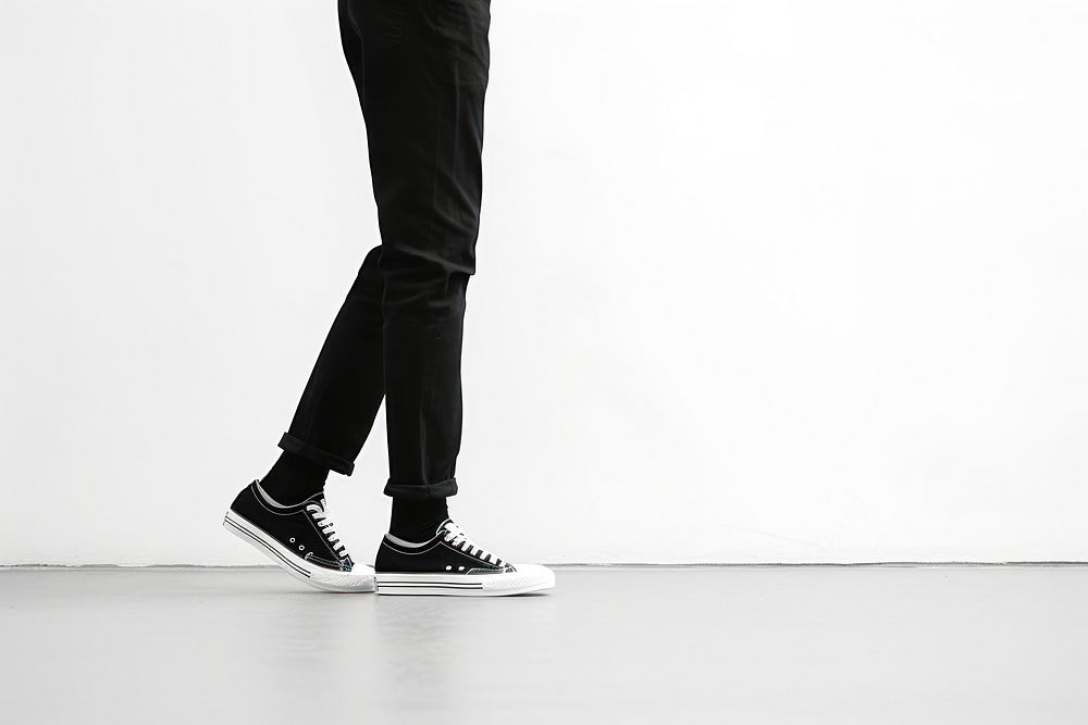 Person in black pants and black and white sneakers footwear walking shoe. AI generated Image by rawpixel.