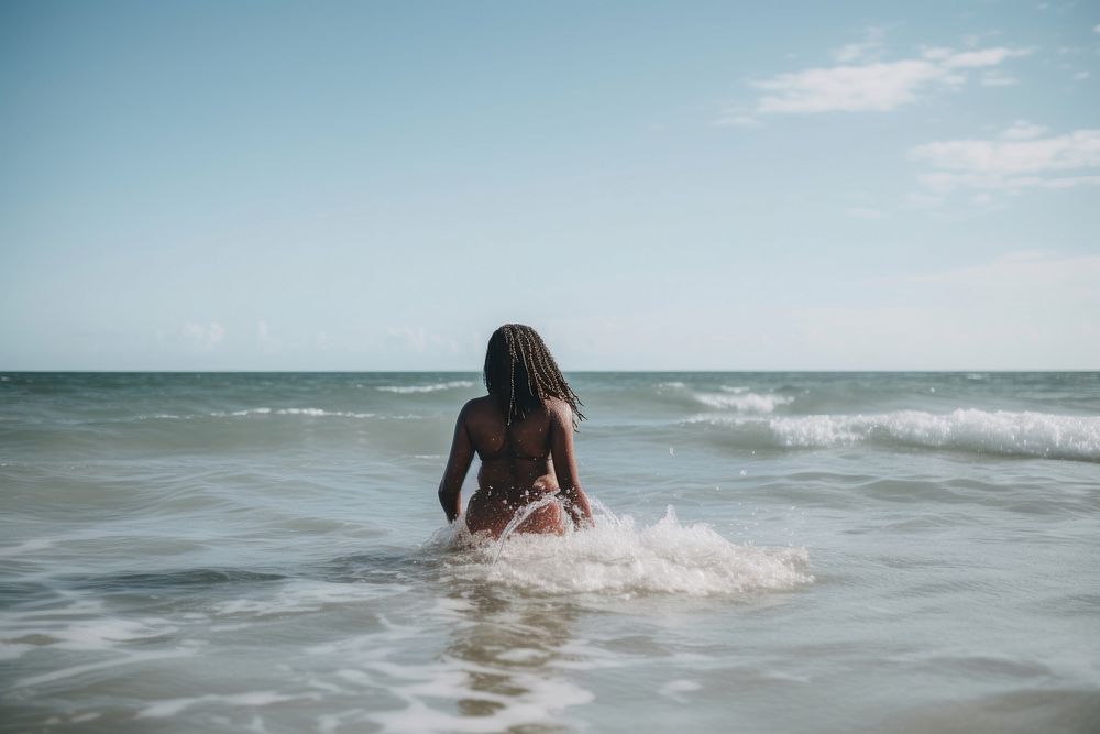 Young black woman wading into ocean swimwear outdoors vacation. AI generated Image by rawpixel.