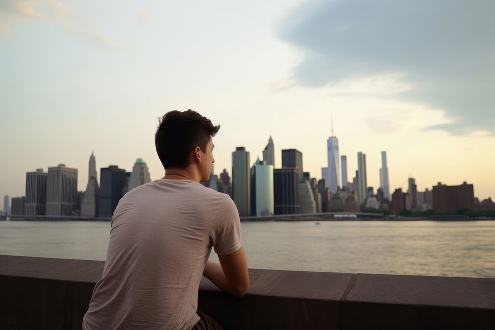 Young man looking out at Manhattan skyline architecture photography skyscraper. AI generated Image by rawpixel.